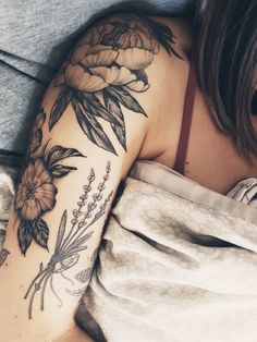 a woman laying in bed with her arm tattooed