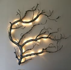 a decorative tree with lights on it is mounted to the wall in front of a bed