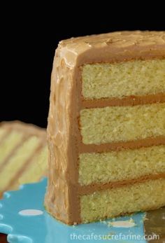 a slice of cake with frosting on top sitting on a blue and white plate