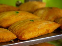 several pastries on a metal tray in a display case with green walls behind them