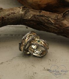 two wedding rings sitting next to each other on top of a piece of driftwood