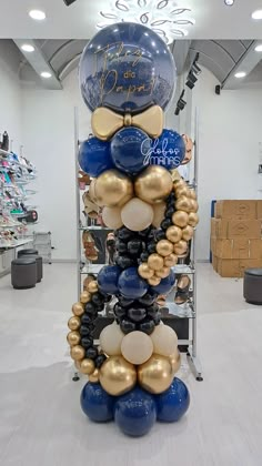 a large balloon tower in a store filled with blue, gold and white balloons