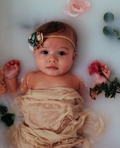 a baby in a bathtub with flowers around it