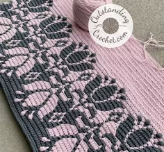 a pink and gray crochet afghan with a ball of yarn next to it