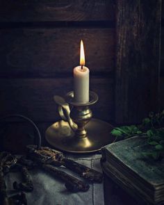 a lit candle sitting on top of a table next to an old book and other items