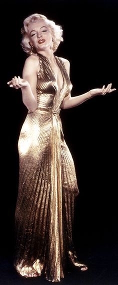 a woman in a gold dress with her arms out and one hand outstretched to the side