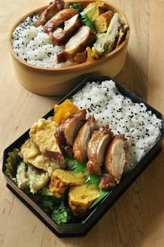 two bowls filled with rice and meat on top of a wooden table