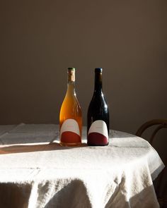 two bottles sitting on top of a table next to a white cloth covered tablecloth