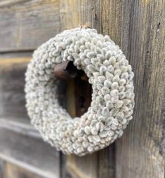 a wreath hanging on the side of a wooden door that is covered in white yarn