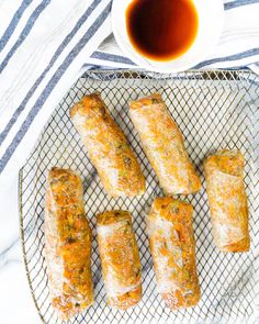 several rolls on a cooling rack with dipping sauce next to it and a cup of tea