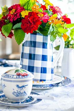 a blue and white pitcher filled with flowers on top of a table