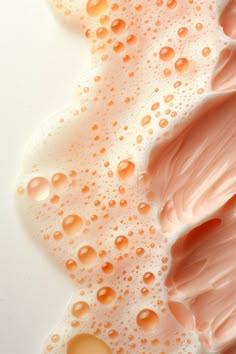 an image of some pink and yellow liquid on a white surface with drops of water