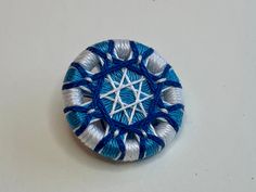 a blue and white brooch sitting on top of a table next to a wall