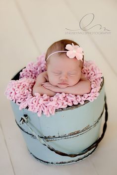 a baby is sleeping in a bucket with pink crochet on it's head