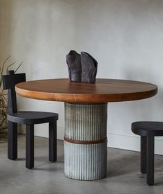 a wooden table sitting next to two black chairs and a vase on top of it