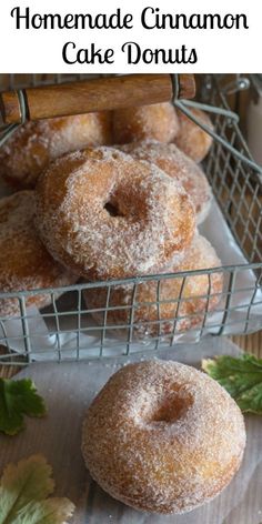 homemade cinnamon cake donuts in a wire basket with leaves and cinnamon sticks on the side