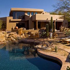 a large house with a pool in front of it and some chairs around the pool