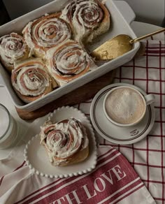 cinnamon rolls in a baking dish and coffee on a table with red checkered cloth