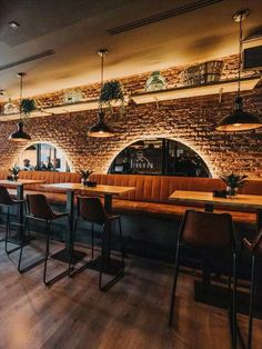 the interior of a restaurant with wooden tables and brown leather chairs, exposed brick wall