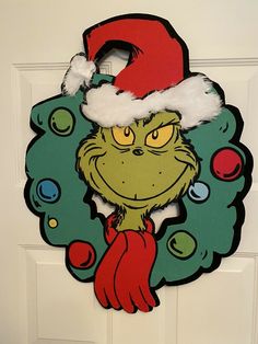 the grinch door hanger is decorated with santa's hat