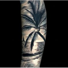 a man's arm with a palm tree and sailboat in the ocean on it