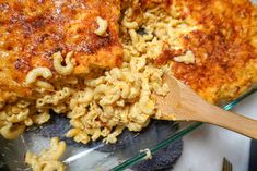 a casserole dish with macaroni and cheese being stirred by a wooden spoon