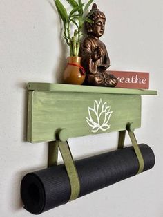 a buddha statue sitting on top of a wooden shelf next to a yoga mat and potted plant