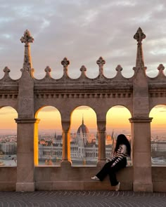 a woman sitting on top of a stone wall next to an arch with arches and crosses