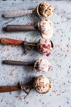 four scoops of ice cream on a table with sprinkles