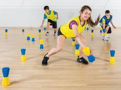 a group of young people playing with plastic cups on a wooden floor in a gym