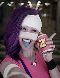 a woman with purple hair and bandages on her face holding up a can of energy drink