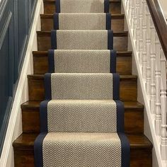 a carpeted stair case with blue trim and white handrails on the stairs