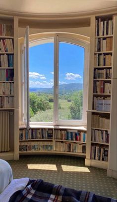 a bedroom with a large window and bookshelves filled with books on the shelves