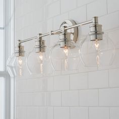 a bathroom light with five bulbs hanging from it's side in front of a window