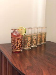 a row of glasses filled with different types of drinks on top of a wooden table