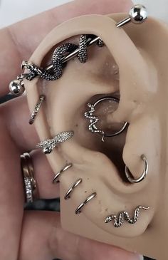 a person is holding an ear with several different types of piercings on the inside of it