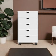 a white dresser sitting next to a plant in a living room