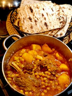 a large pot filled with food next to some pita bread