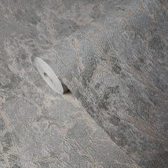 a roll of toilet paper sitting on top of a gray stone wall with cracks in it