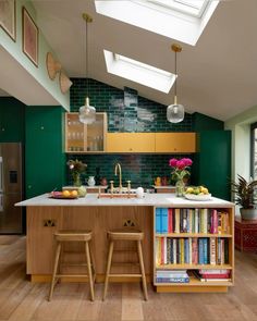 a kitchen with two stools in front of an island and bookshelves on the wall