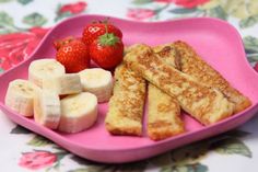 a pink plate with bananas, strawberries and other food items on top of it