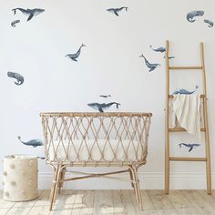 a baby crib in front of a white wall with whale decals on it