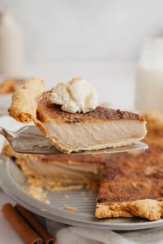 a piece of pie is being held up by a fork with whipped cream on top