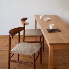 two chairs sitting at a table with cups on it and a cell phone next to them