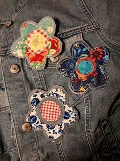 three patches are placed on the back of a jean jacket, one with an applique