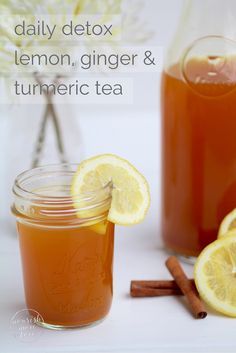 a jar of lemon ginger tea next to some sliced lemons and cinnamon sticks on a white table