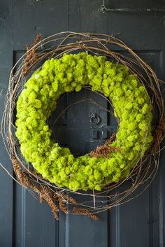 a wreath with moss is hanging on the front door