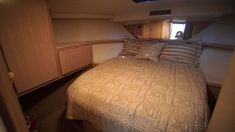 a bed in a small room with wooden cabinets and drawers on either side of the bed