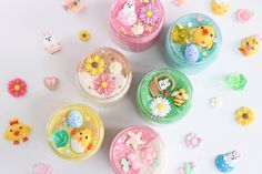 several small plastic containers filled with different types of candies and flowers on a white surface