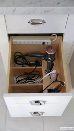 an open drawer with hair dryers and other items in it on the counter top